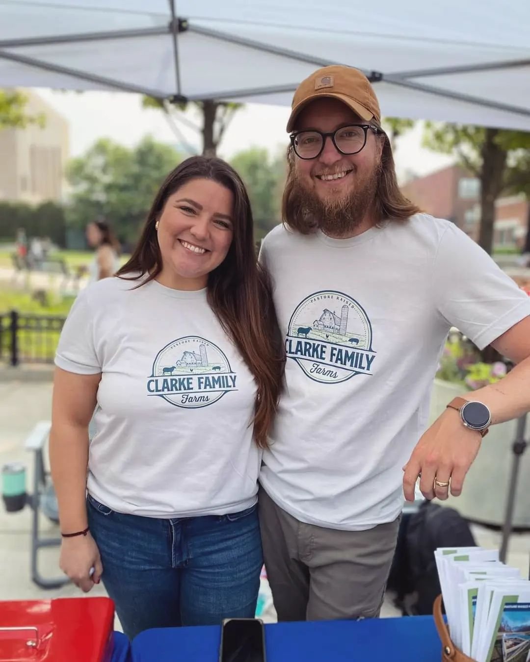 Smiling couple at a farmers market booth wearing matching 